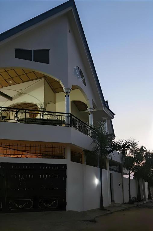 a white house with a balcony and a palm tree at Villa Privée in Abomey-Calavi