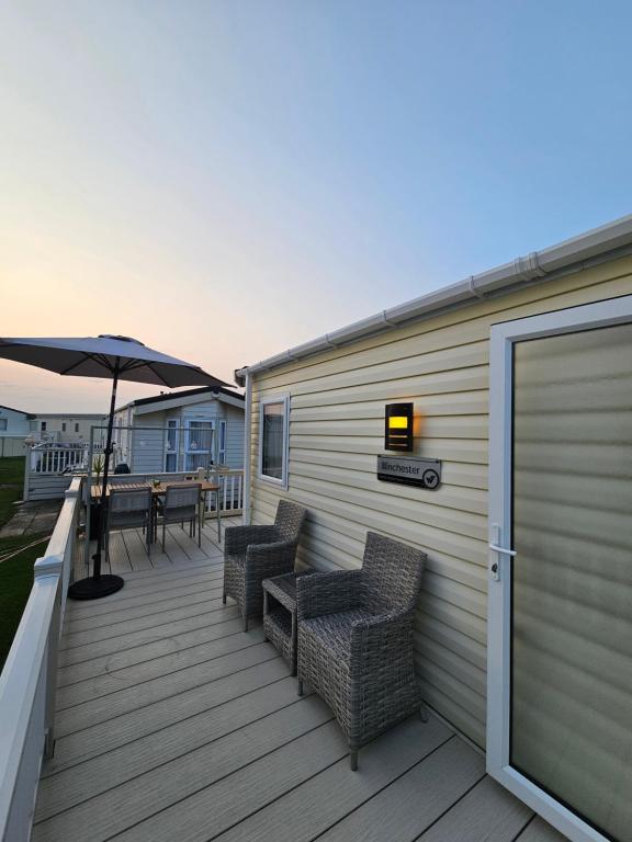 a deck with a table and chairs and an umbrella at Robins Sunset Holiday Home in Seasalter
