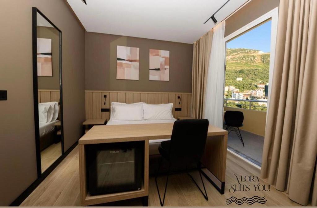 a room with a bed and a desk and a window at Apandnrosm in Vlorë