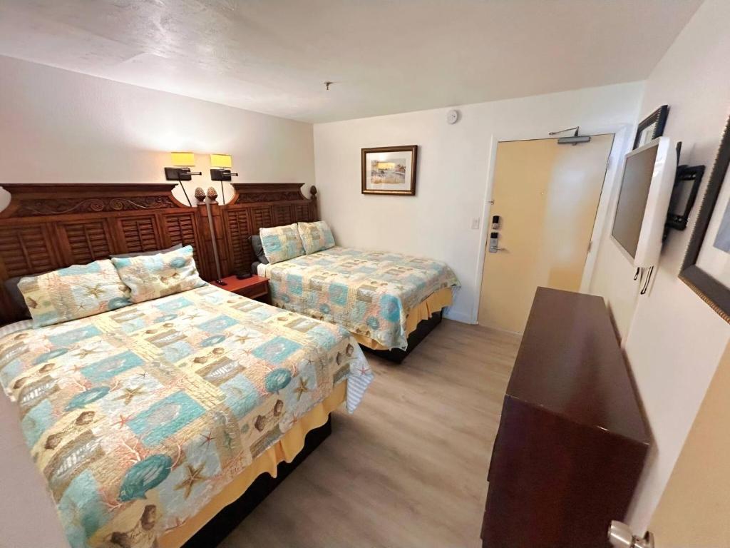 Una habitación de hotel con dos camas y un espejo. en Direct beach access 1st Floor walkout w/kitchen, en Daytona Beach
