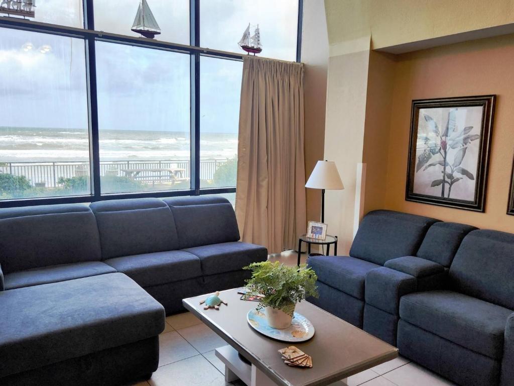 a living room with blue couches and a large window at Daytona Beach 1 bdrm Oceanfront Luxury Condo in Daytona Beach