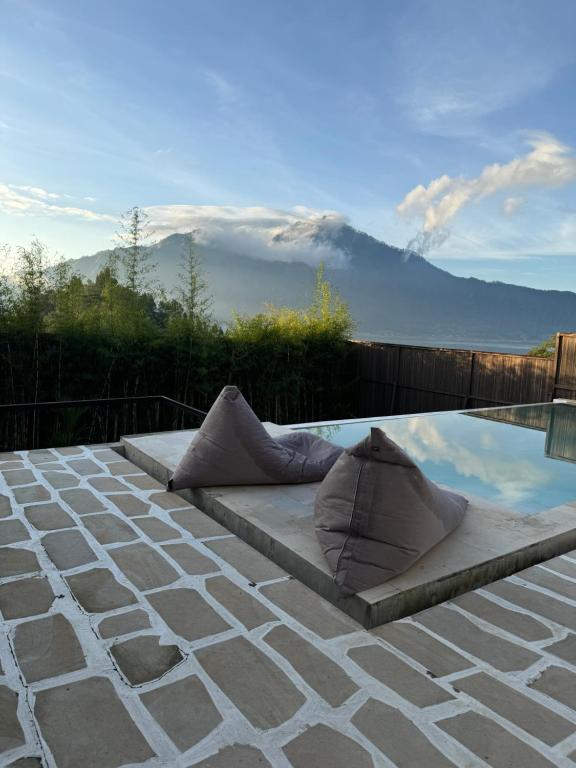 a pool with pillows on a patio with a view of a mountain at Enla Montana villa private pool and hot spring in Kubupenlokan