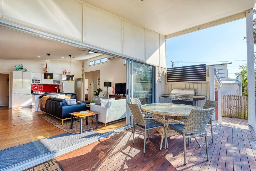 a dining room and living room with a table and chairs at Delightful Dicky Beach Holiday House in Caloundra