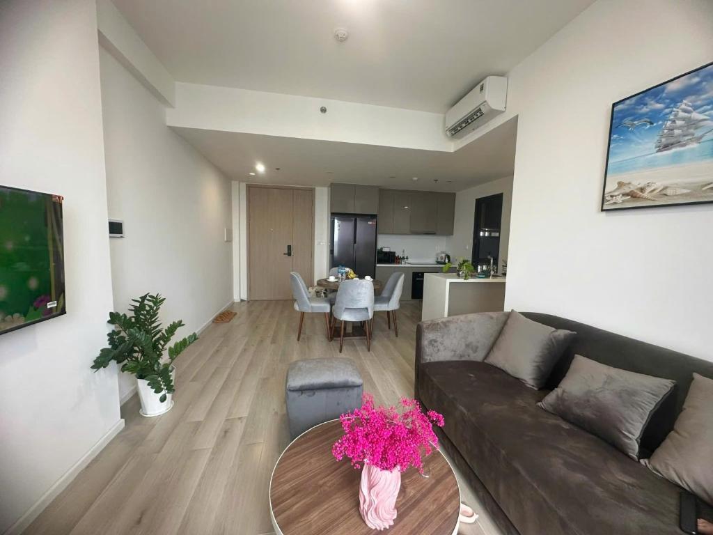 - un salon avec un canapé et une table ornée de fleurs roses dans l'établissement Căn hộ cao cấp Masteri Centre Point Vinhomes Grand Park Quận 9 TPHCM, à Gò Công