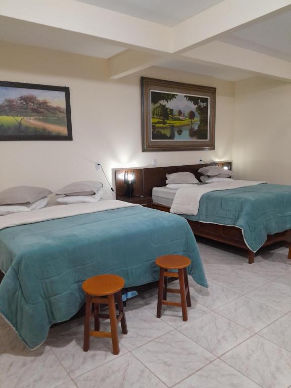 a hotel room with two beds and two stools at Hotel e Pousada Ciconha-são Lourenço MG in São Lourenço
