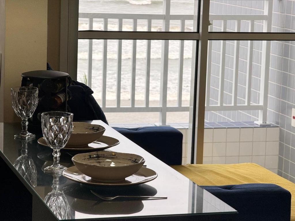 a table with two bowls and wine glasses on it at Refúgio do Aconchego Frente Praia Ocean Club in Mongaguá