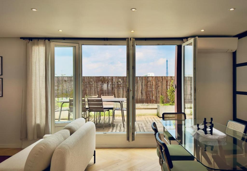 - un salon avec une table en verre et une salle à manger dans l'établissement Cocoon 6p, Terrace with Eiffel Tower & Seine View, à Paris