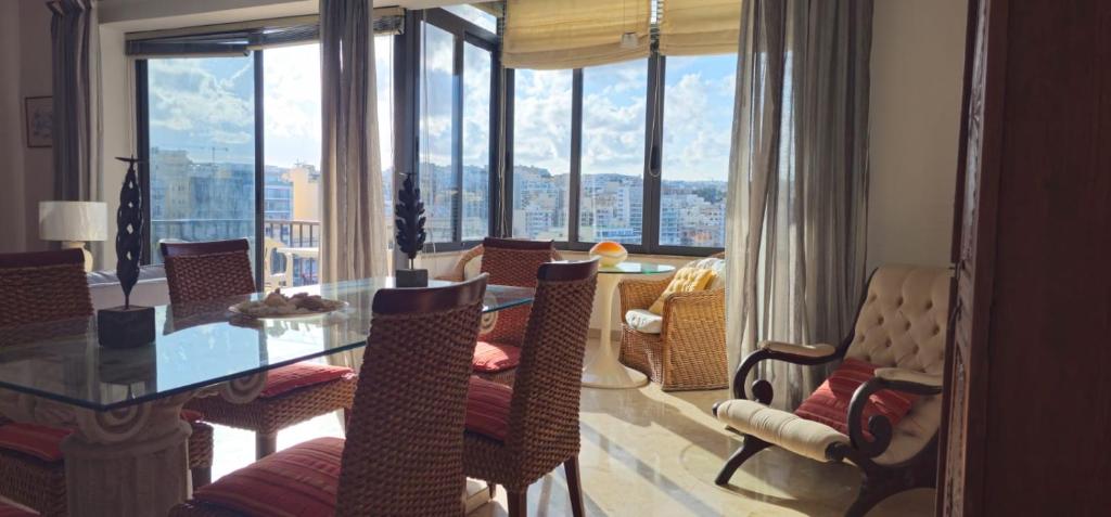 un salon avec une table, des chaises et des fenêtres dans l'établissement Waterfront Panorama Massive Three Bedrooms Flat S8, à Sliema
