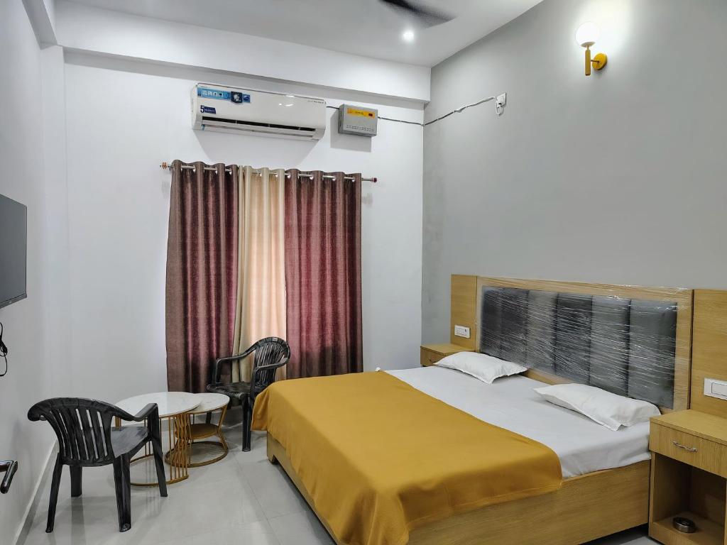 AyodhyaHotel Paramount Inn的一间卧室，配有一张床、一张桌子和几把椅子