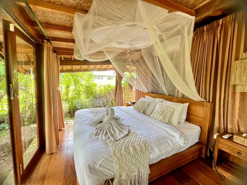 a bedroom with a canopy bed with white sheets at Joglo Valley Villa by Rare Angon Ubud in Ubud