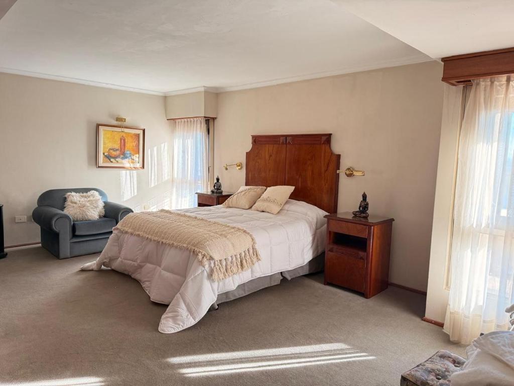 a bedroom with a large bed and a chair at Decimo in Villa Mercedes