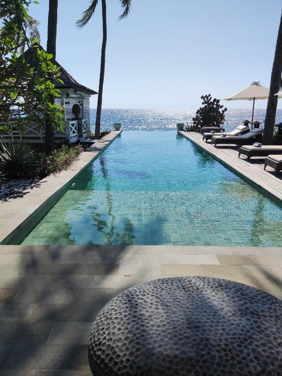 a swimming pool with a view of the ocean at Beach Villa Pantai Matanai in Tianyar