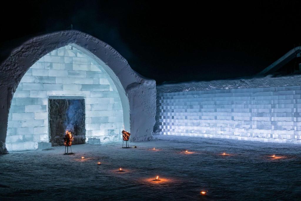 a person standing in front of an igloo at night at Ice Hotel in Jukkasjärvi
