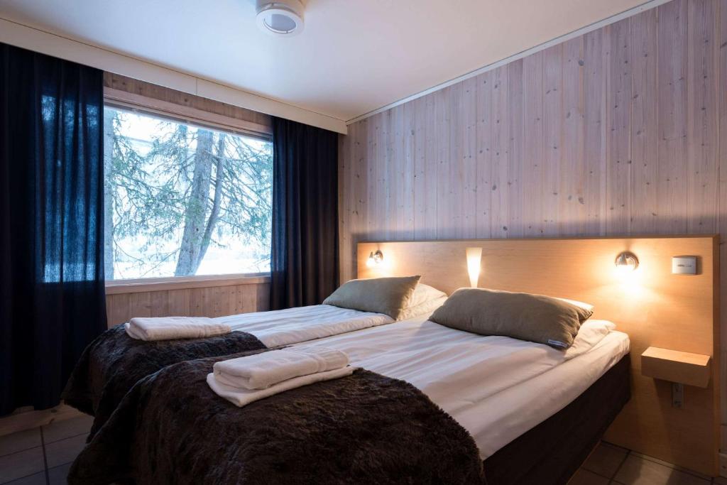 two beds in a room with a large window at Ice Hotel in Jukkasjärvi