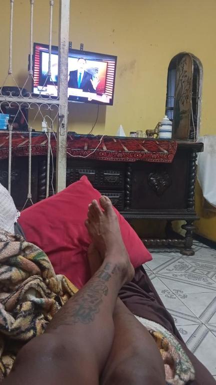 a man laying on a bed with his foot on a pillow at Casa de casal in Duque de Caxias