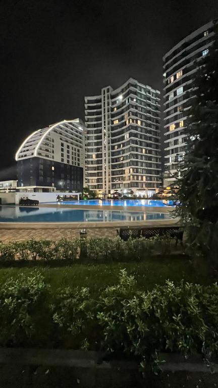 a train traveling past tall buildings at night at Квартира у моря с бассейном in Batumi