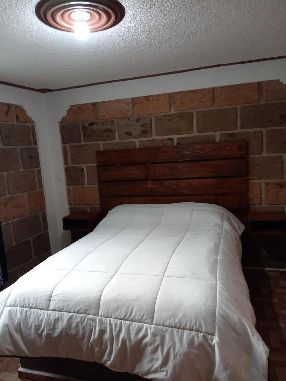 a bedroom with a white bed with a brick wall at Hotel familiar los Fresnos in Santiago Oxtempan