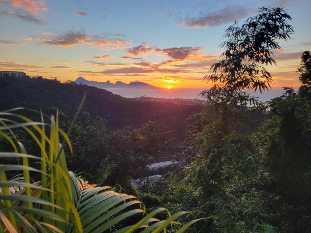 a sunset in the mountains with a river and trees at Papeete Secret Spot in Papeete