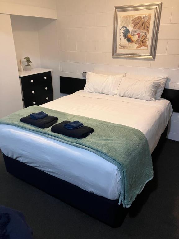 a bedroom with a bed with two towels on it at Trentham Motel in Upper Hutt