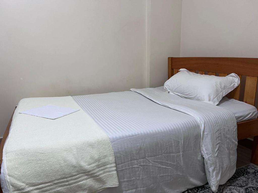 a bed with a white comforter and a pillow at The Skyline Loft in Juja