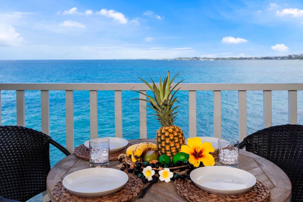 une table avec des assiettes et un ananas au-dessus de l'océan dans l'établissement Sea Village 4213, à Kailua-Kona