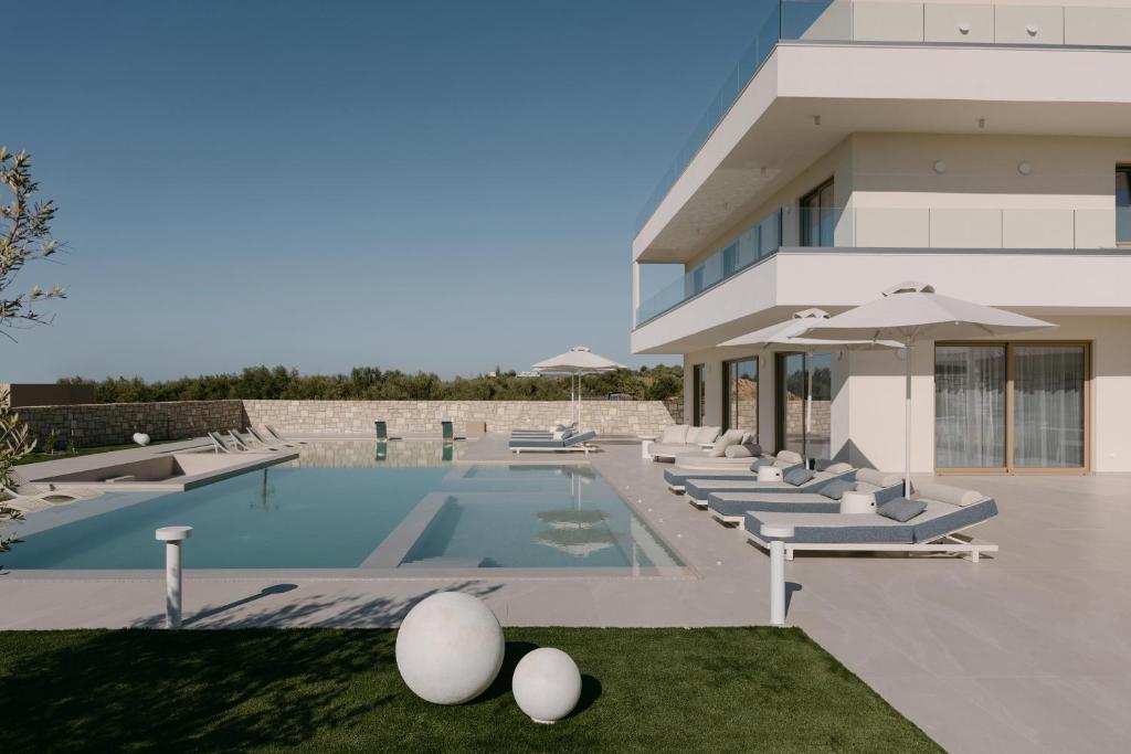 a building with a swimming pool with lounge chairs at Calòre Villa, Close to Beach, Gym, Sauna & Cinema, By ThinkVilla in Pigianos Kampos