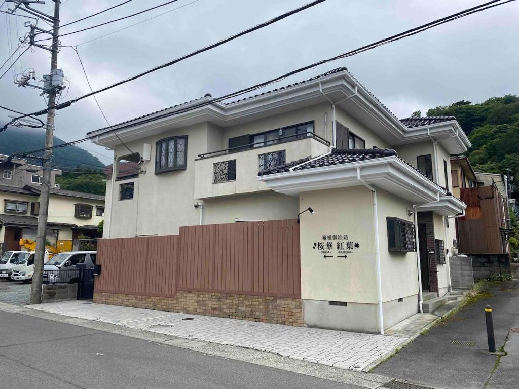 a white house with a red fence on a street at 箱根御泊処-紅葉- 049bH in Hakone