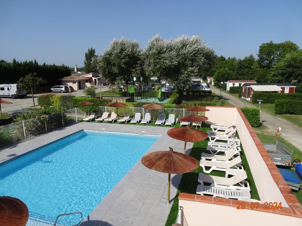 a swimming pool with chairs and umbrellas at Cottage 4 personnes in Mirepoix