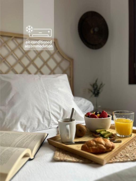 a tray of food and fruit on a bed at Numancia Suites in Soria