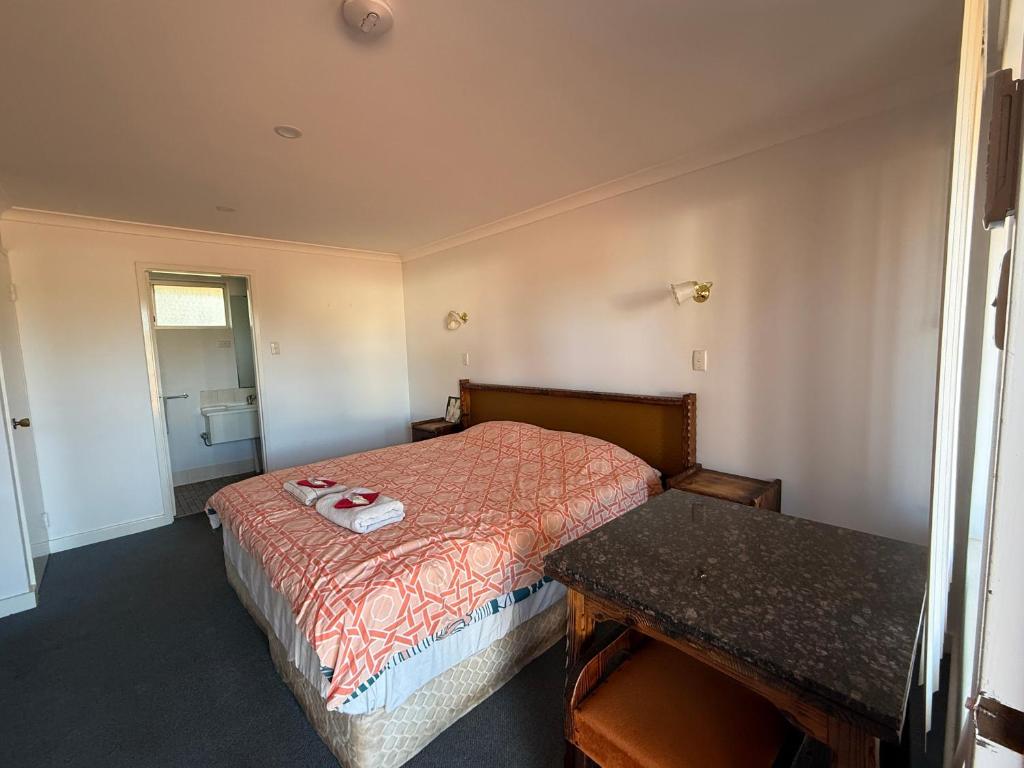 une petite chambre avec un lit et une table dans l'établissement Kondinin Roadhouse Motel, à Kondinin