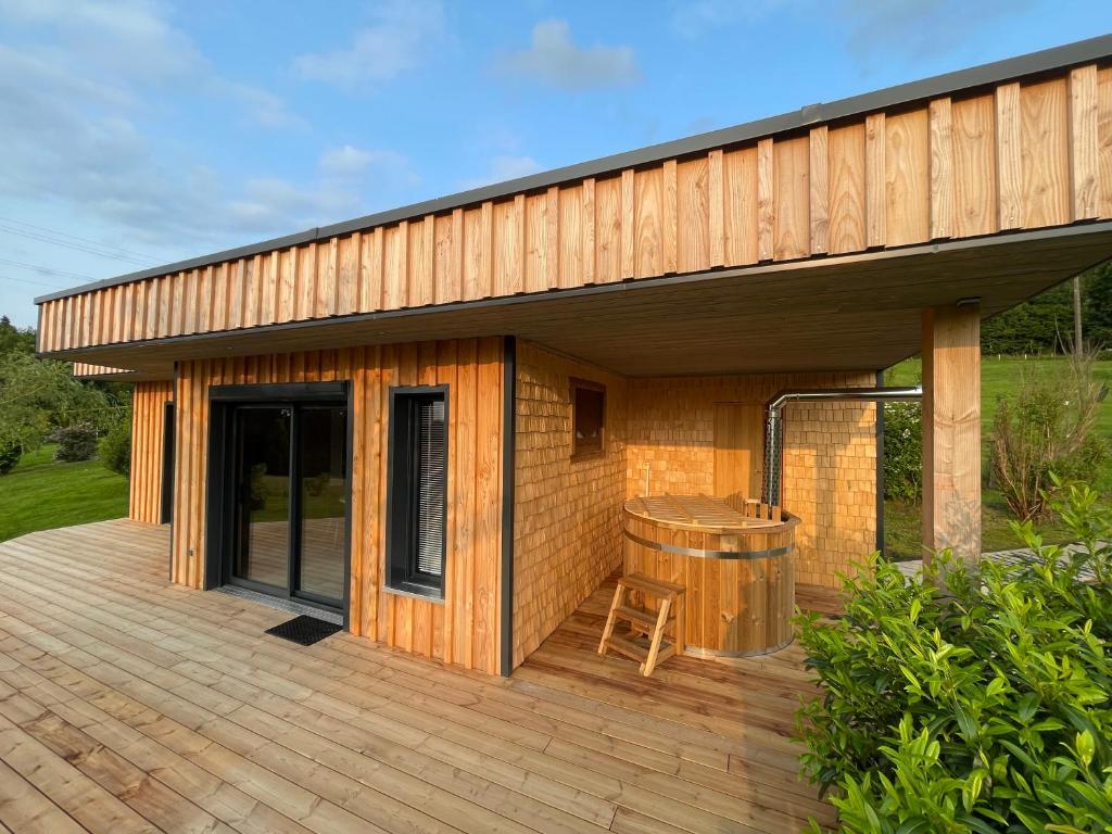 une maison avec une terrasse en bois et une table dans l'établissement Nature Cottage Vosges Spa Le Cerf, à Anould