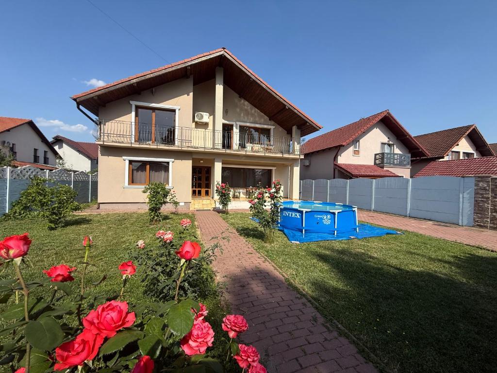 a house with red roses in the yard at Villa cu 4 dormitoare de 3 stele Timiș, perfectă pentru familii sau grupuri in Utvin