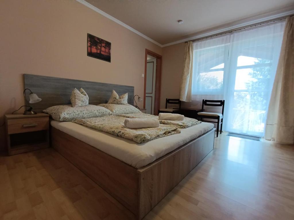 sypialnia z dużym łóżkiem i dużym oknem w obiekcie Vitorlás Apartmanház w Siófoku