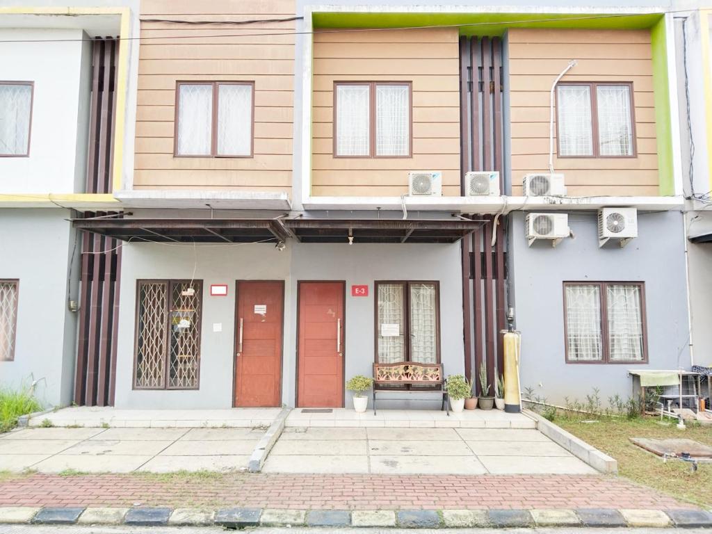 a house with red doors and a bench in front of it at Colombus Homy Syariah in Karawang