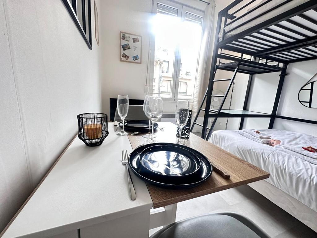 une pièce avec une table avec une assiette et des verres à vin dans l'établissement Talleyrand studio neuf cozy hyper centre, à Reims