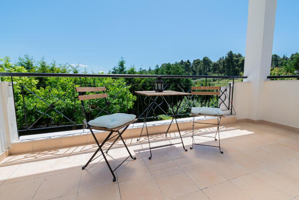 two chairs on a balcony with a view of trees at Sofia Maisonette by RentalsPro - Sani Halkidiki in Sani Beach