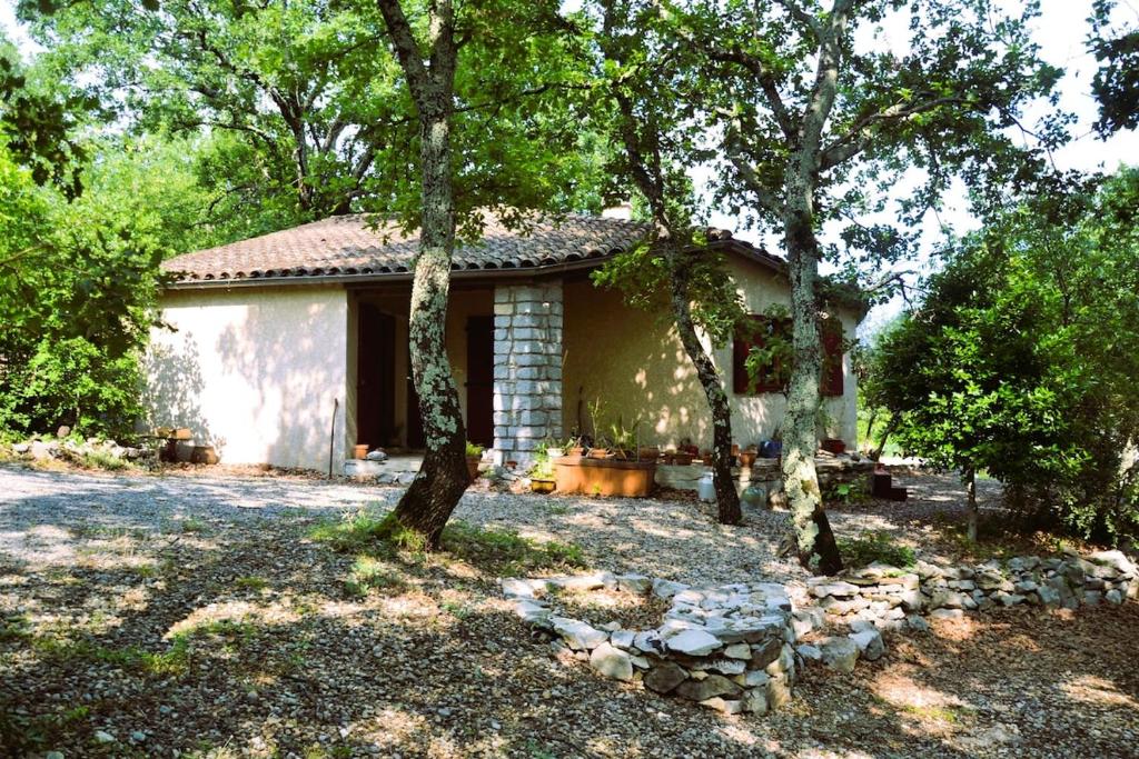 une petite maison avec des arbres devant elle dans l'établissement Maison sous les chênes, à Saint Alban Auriolles