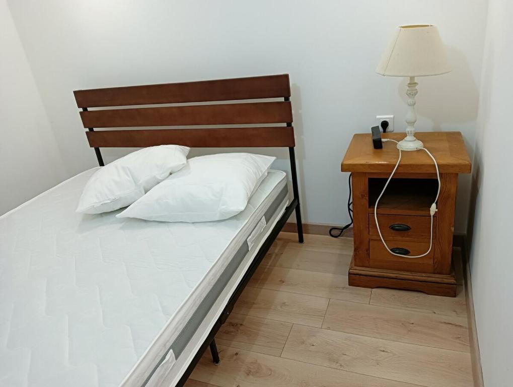 - une chambre avec un lit, une table de chevet et une lampe dans l'établissement Gîte de la Fauvette, à Le Buisson Genois