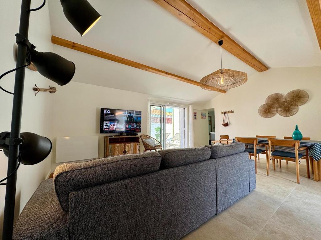 un salon avec un canapé et une salle à manger dans l'établissement La Parenthèse Olonnaise & Maison Familiale, à LʼÎle-dʼOlonne