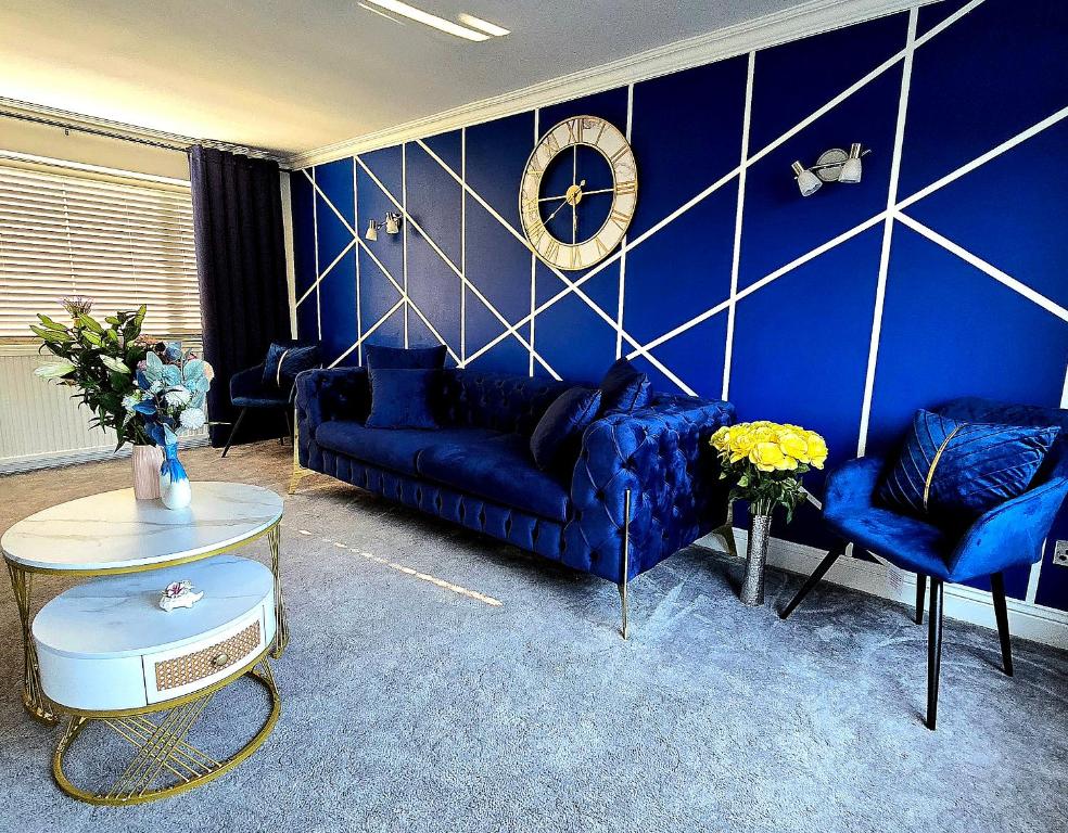 a blue living room with blue couches and a clock at Luxury Modern Comfy 3BR House Contractors Family in Kettering