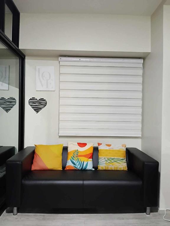 - un canapé noir avec des oreillers colorés dans l'établissement 2 BEDROOM CONDO close to SM Tungko BULACAN ideal for Family Queen bed on Bedroom 1 accessible to Bedroom 2 with sliding doors Free Wifi & Netflix to watch in a comfy sofa & twin bed Access to SWIMMING POOL entry is very affordable and kids get for free, à Tunkong Manga