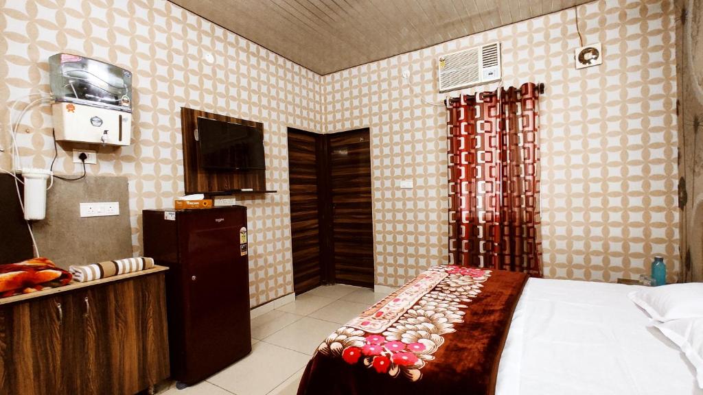 帕格瓦拉SYL HOTELS One - Comfortable and Secure Stays的一间卧室配有一张床,厨房配有电视