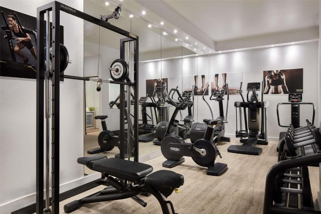 A bright mirrored gym with cardio machines and a cable station.