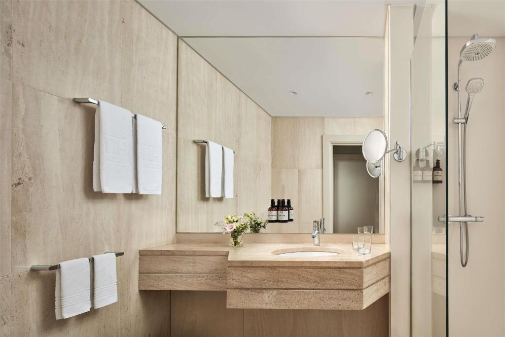 A marble-look bathroom vanity with a large mirror and glass-enclosed shower.