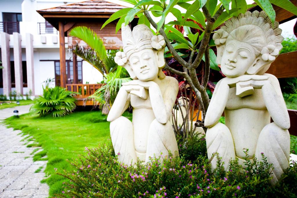 two white statues are sitting in a garden at Ibali Hostel in Magong