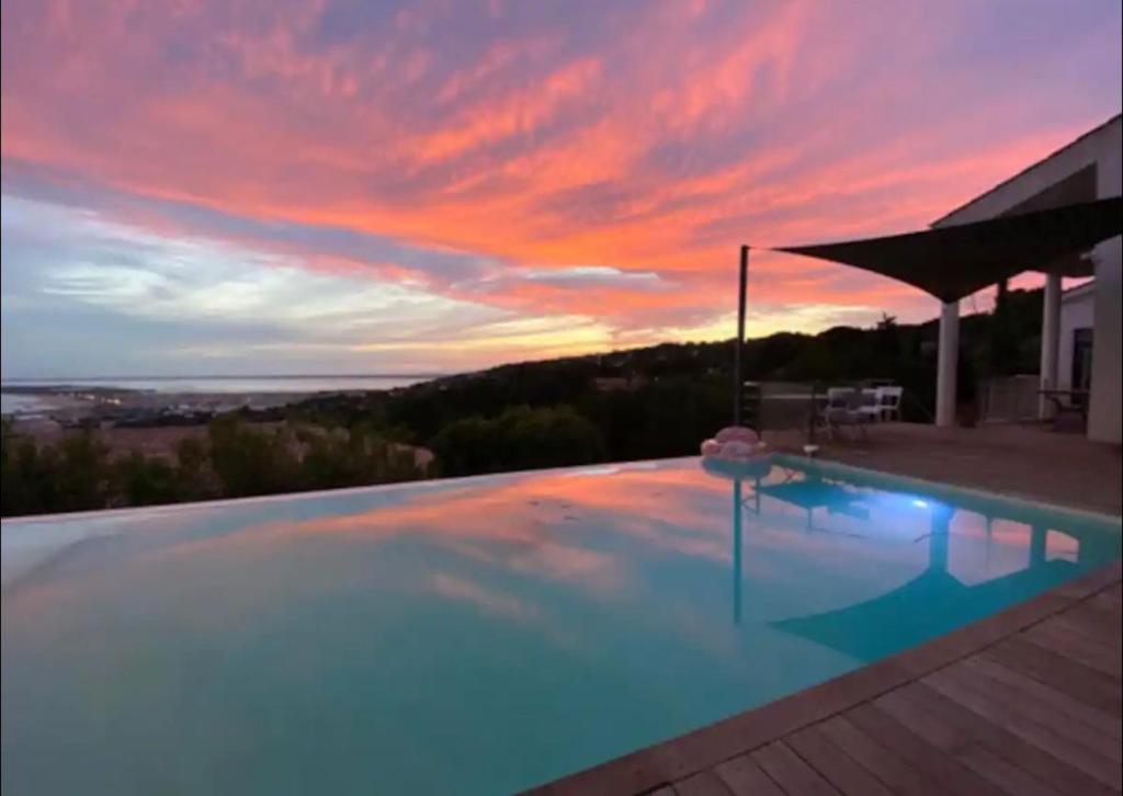 une piscine avec un coucher de soleil en arrière-plan dans l'établissement Superbe Villa sur le mont Saint Clair à Sete, à Sète