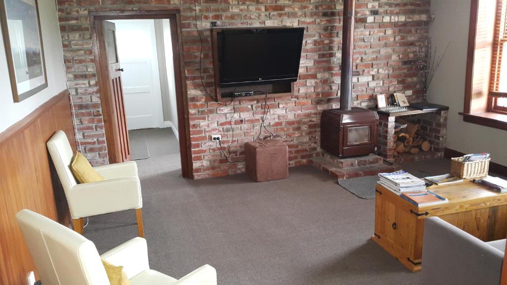 a living room with a brick wall and a television at Waipiata Country Hotel in Waipiata