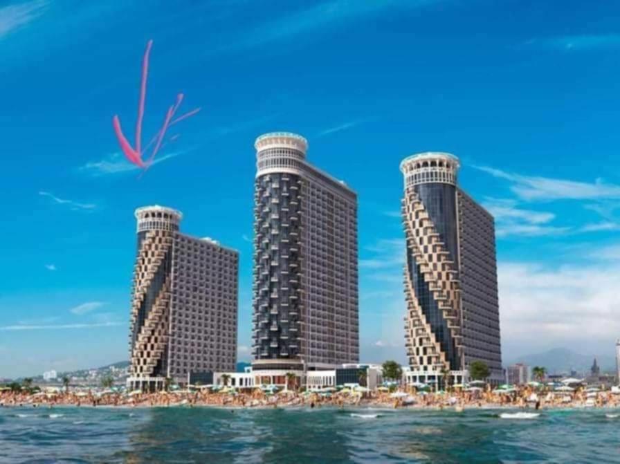 three tall buildings on a beach with a kite in the sky at Apartment Rimma in Batumi