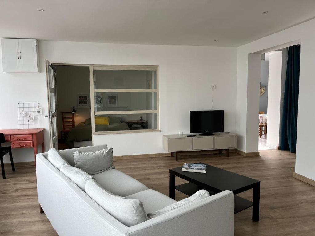 a living room with a white couch and a table at Hébergement retour de plage in Tréffiagat