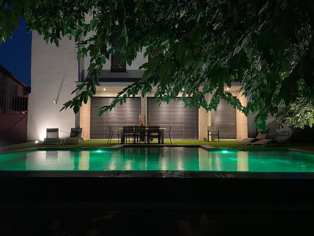- une piscine avec une table et des chaises la nuit dans l'établissement Grande maison atypique avec piscine à débordement, à Bouillargues